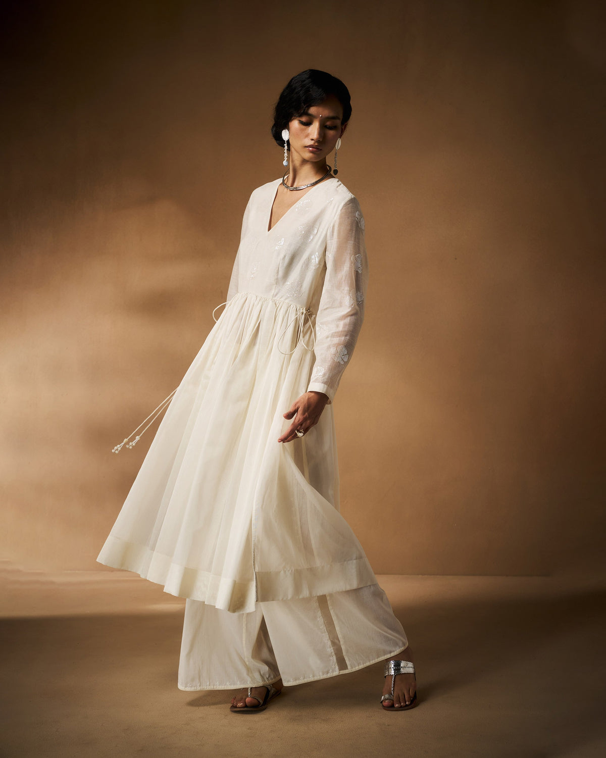 Person wearing a flared ivory Amaya kurta with sheer embroidered sleeves.