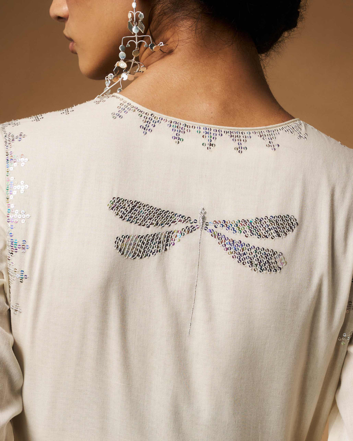 Close-up of an ivory Aafreen Angrakha back with a silver sequin dragonfly.