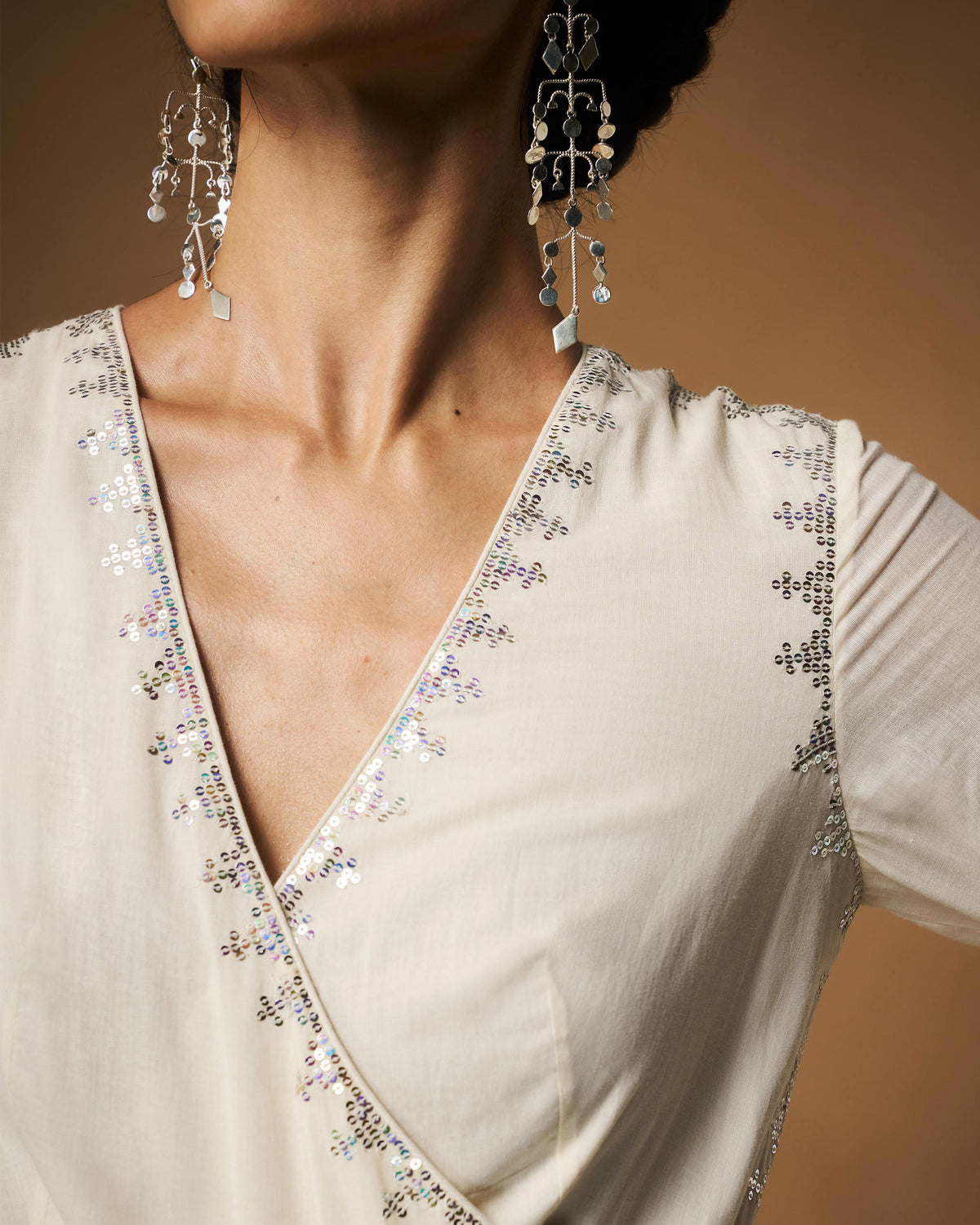 Close-up of an ivory Aafreen Angrakha V-neck with silver sequin embroidery.