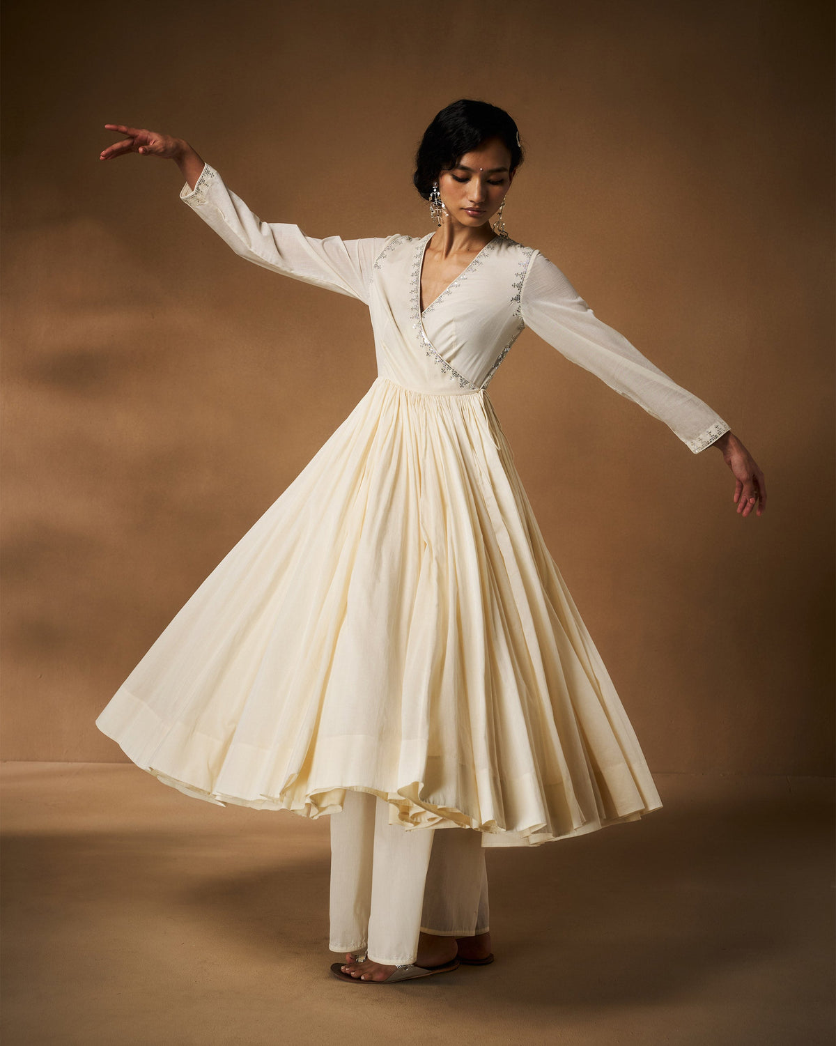 Person twirling in an ivory Aafreen Angrakha with a flared pleated skirt.