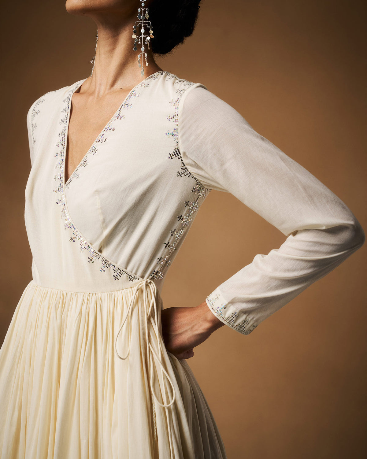 Person wearing an ivory Aafreen Angrakha wrap with silver neckline embroidery.