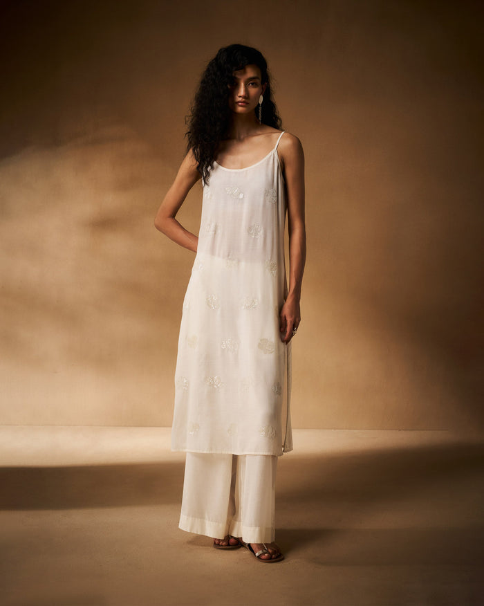 Person wearing an ivory embroidered camisole with thin spaghetti straps.