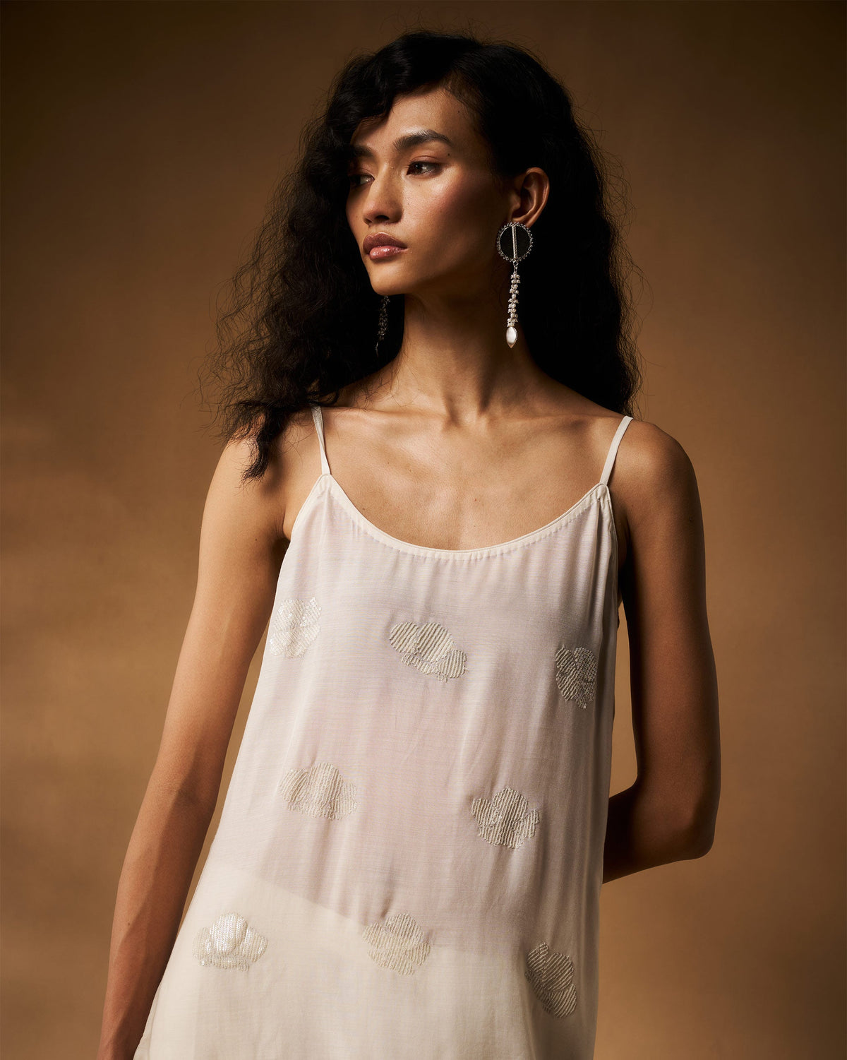 Person wearing an ivory camisole with hand-embroidered floral motifs.