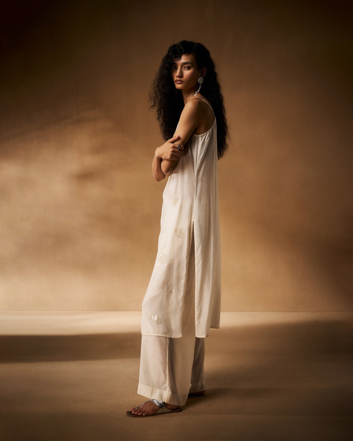 Side view of a long ivory embroidered camisole with side slits.