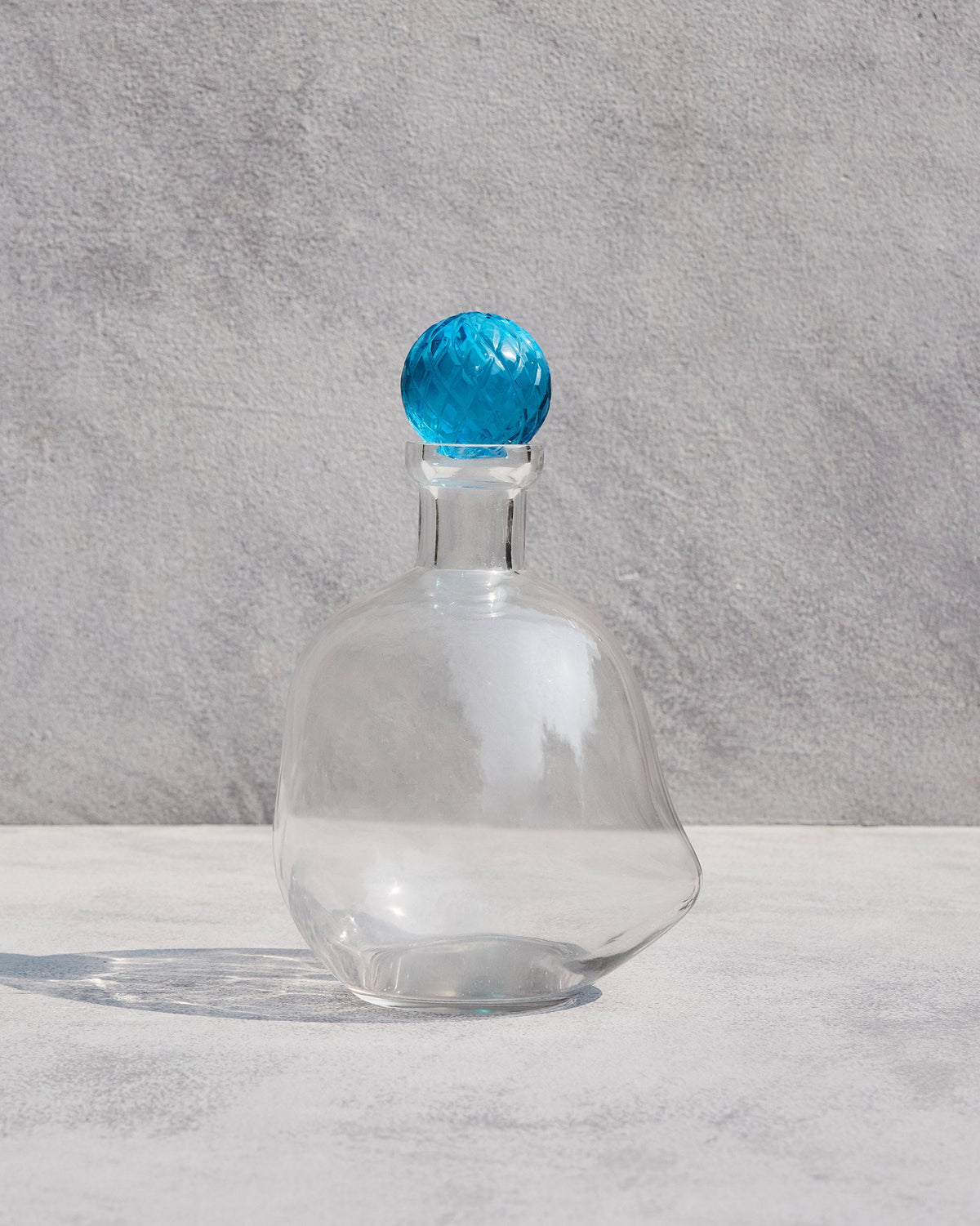 Clear glass Revel Decanters with a faceted blue stopper.