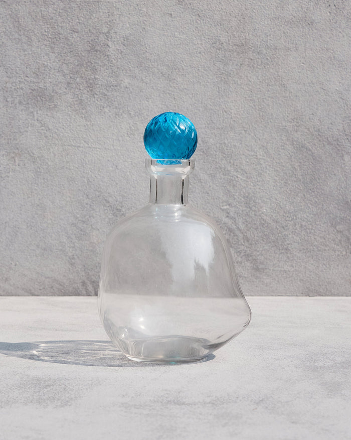 Clear glass Revel Decanters with a faceted blue stopper.