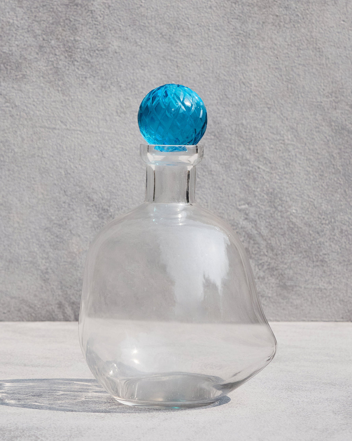 Large Revel Decanter in clear glass with a faceted blue stopper.