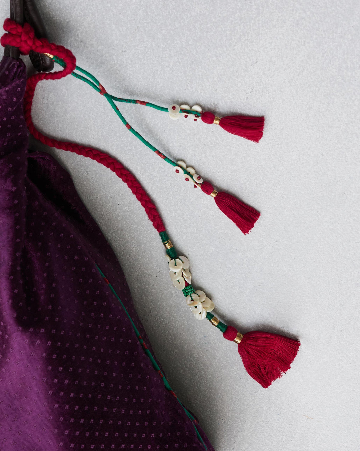 Close-up of a Nomad Tote drawstring with red and green tassels and cream beads.