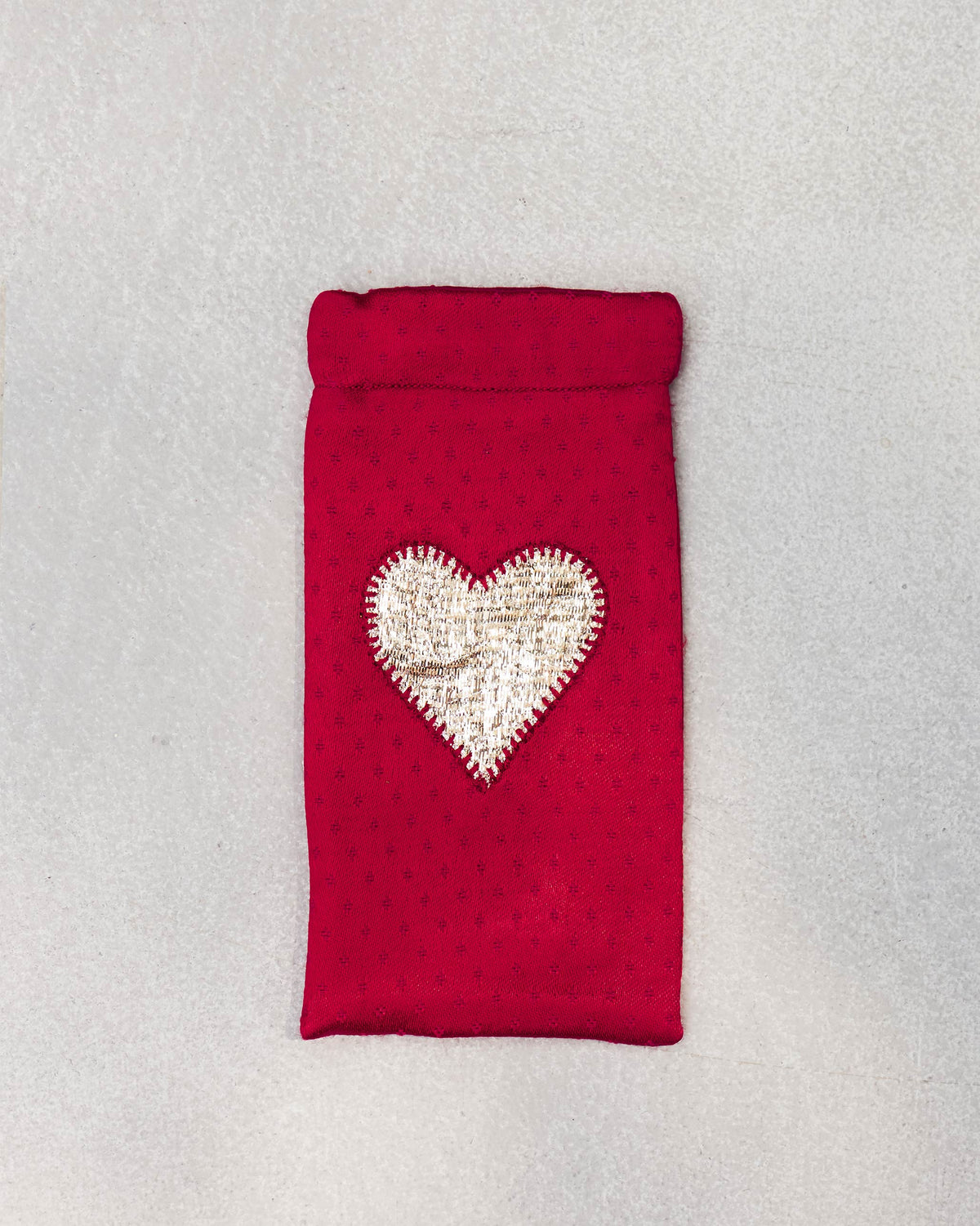 Happy Heart Spec Case laid flat, showing its heart patch on red fabric.