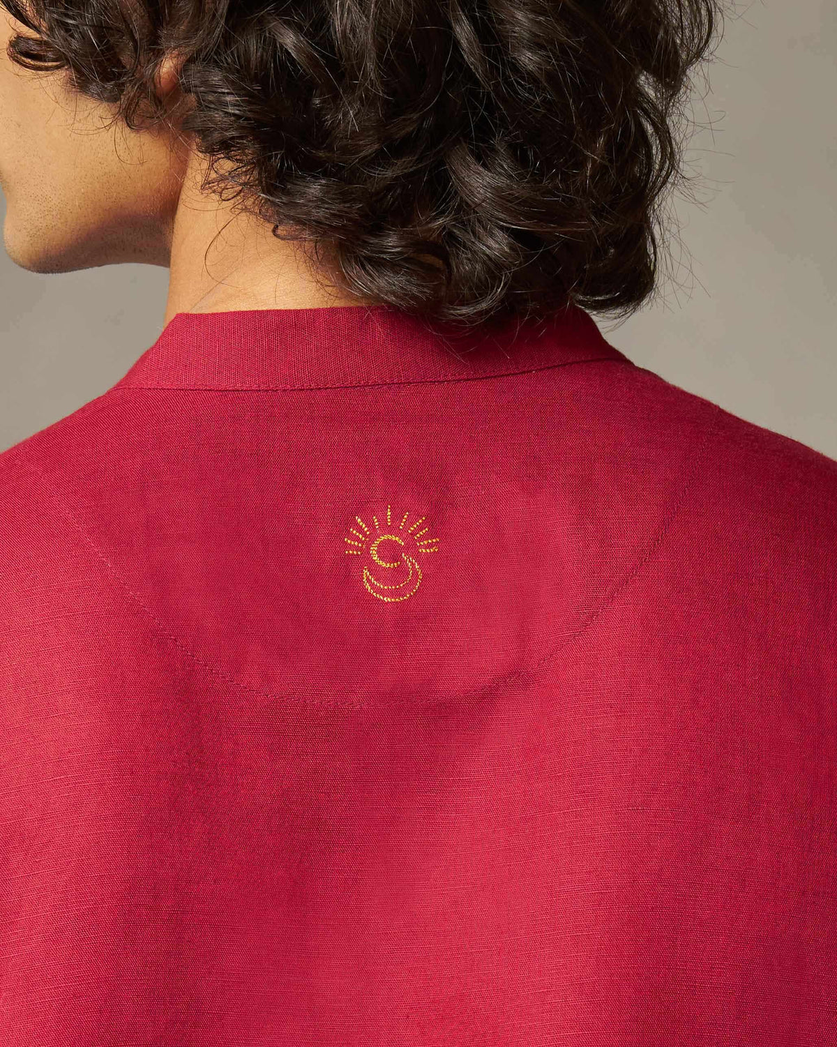 Close-up of a red Staple kurta's back neck with a small gold embroidered sun motif.