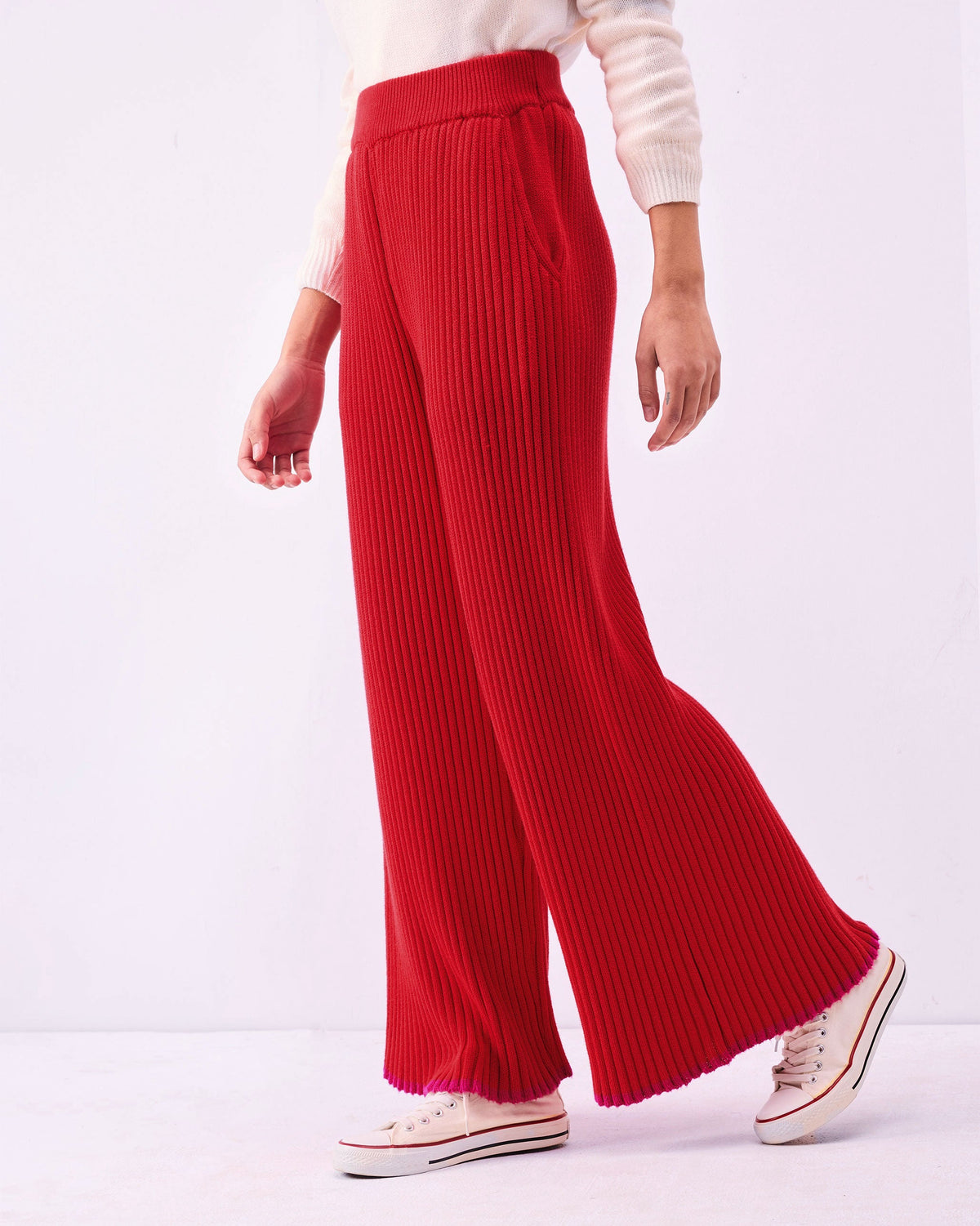 Side view of Ribbed Knit Trousers in bright red with a wide leg and pink-edged hem.
