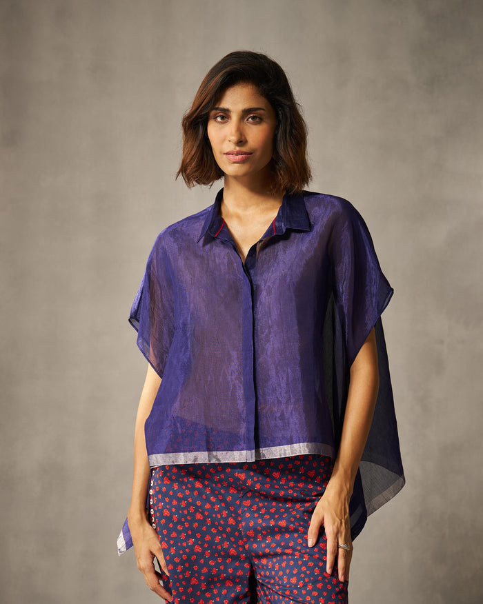 Person wearing a sheer blue-violet top with a silver band at the hem.