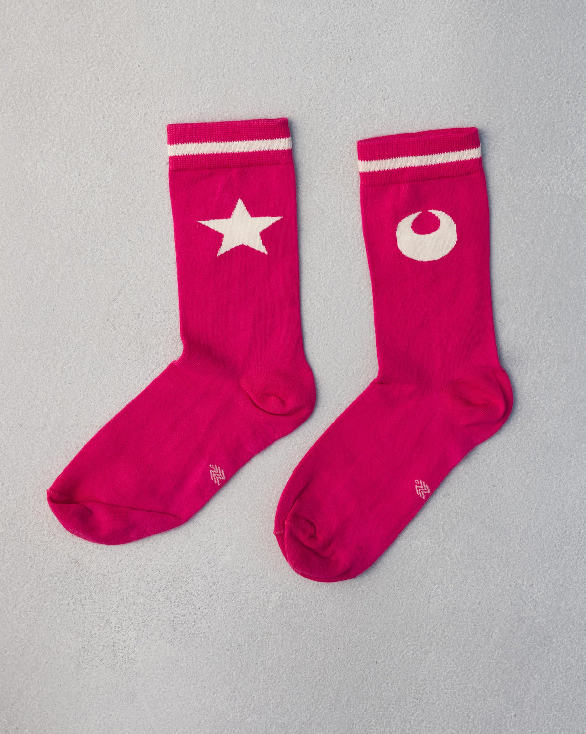Pair of Star & Moon Socks in fuchsia, one with a star and one with a moon.