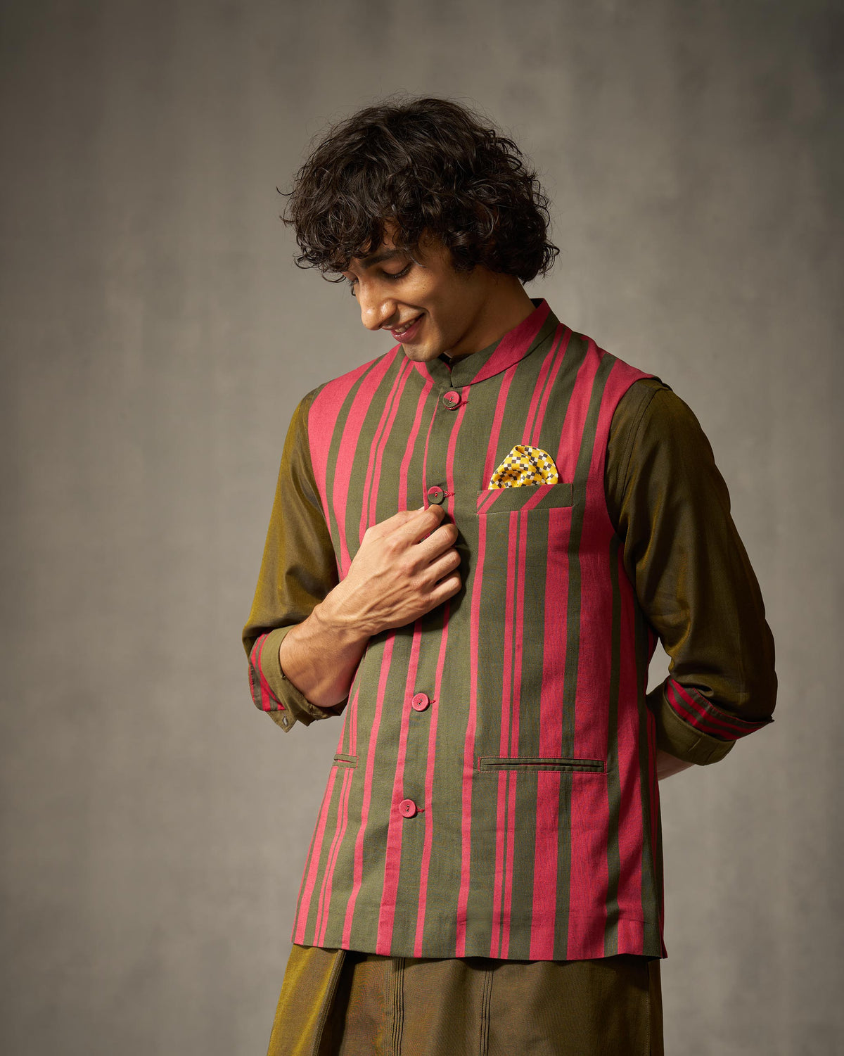 Person wearing a red and oak brown striped Nehru jacket with a pocket square.