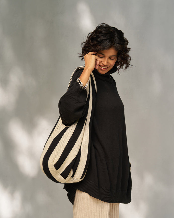 Person wearing a Stripe Bag on one shoulder, with black and ivory knit stripes.