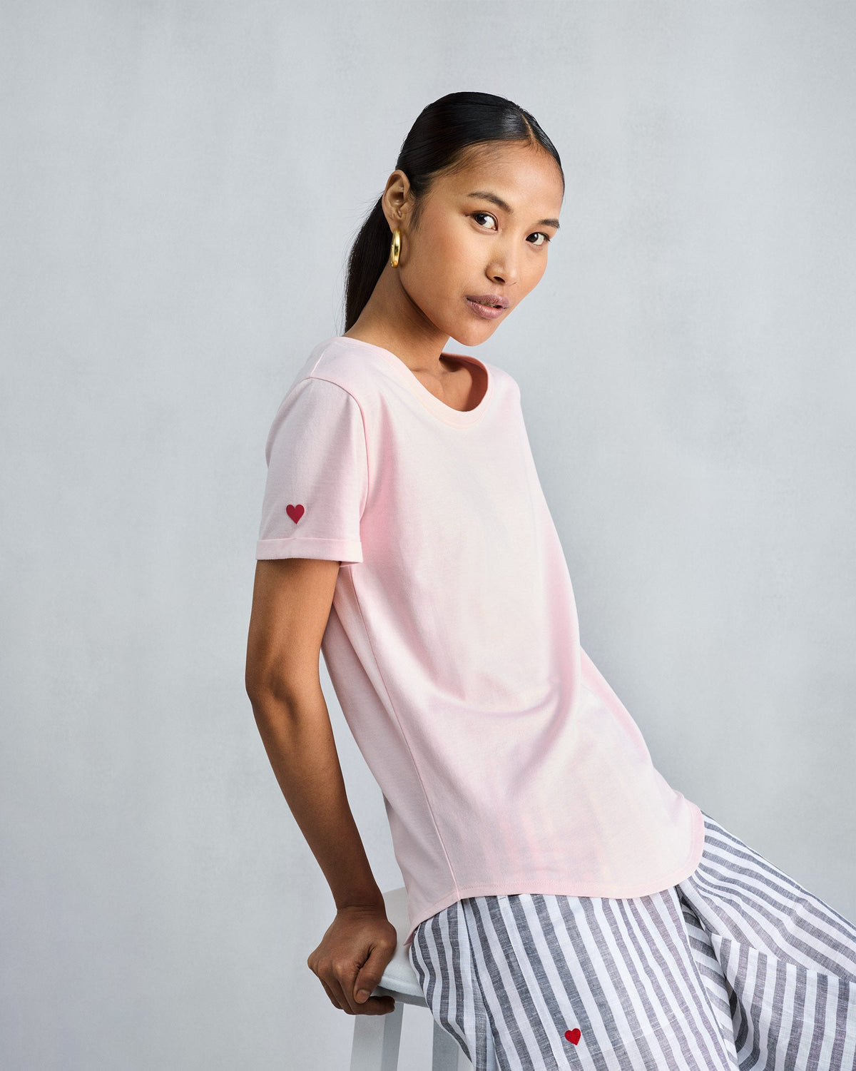 Person wearing the Basic T-Shirt in blush pink with a heart on the sleeve.