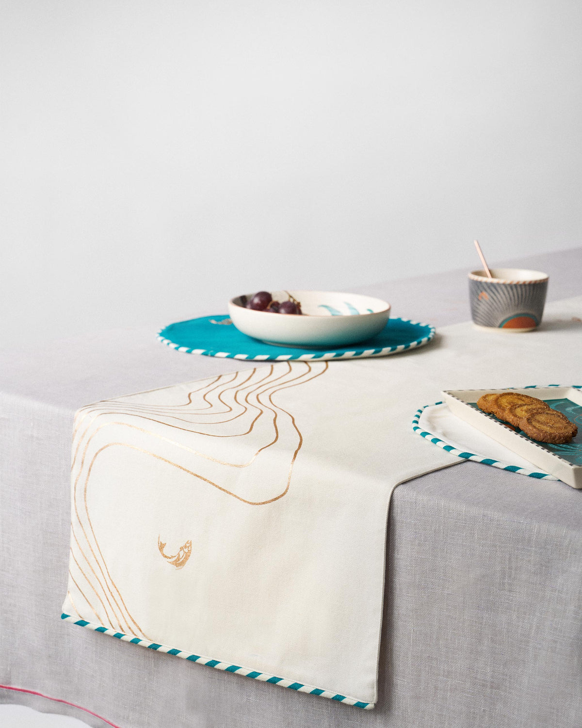 Cascade Runner laid across a table, with brown wavy lines and a teal-striped edge.