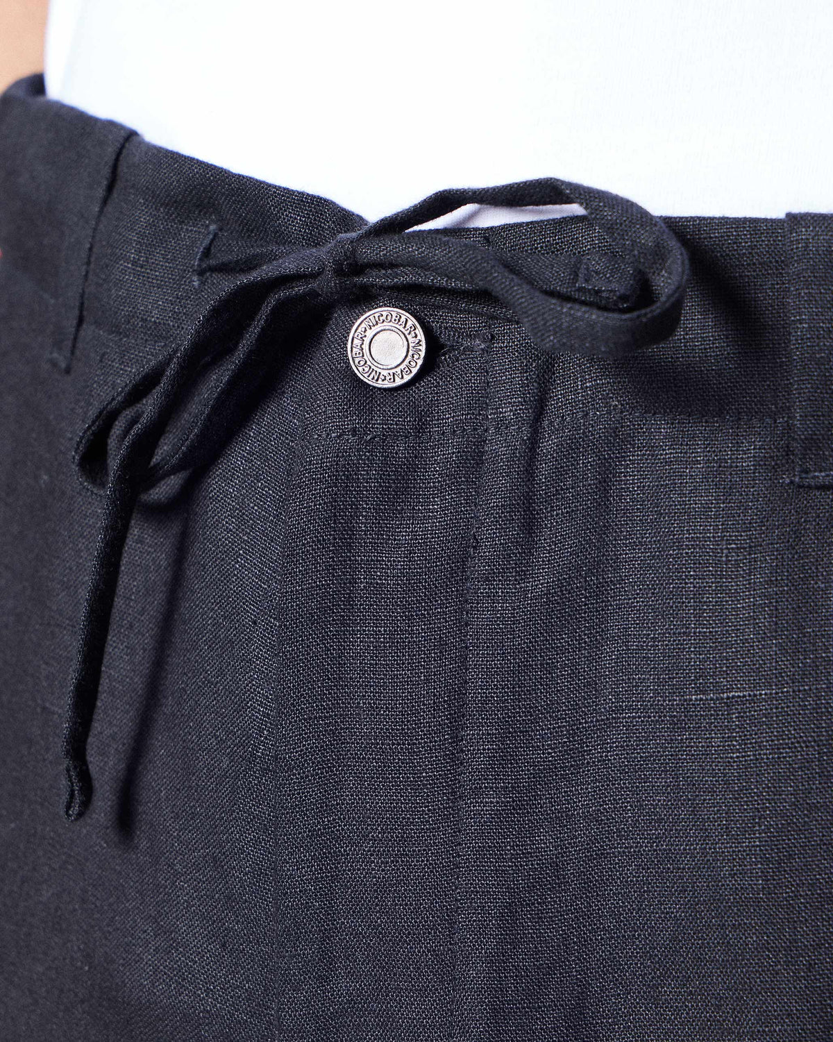 Close-up of black Karo Pants showing the drawstring waist and Nicobar button.