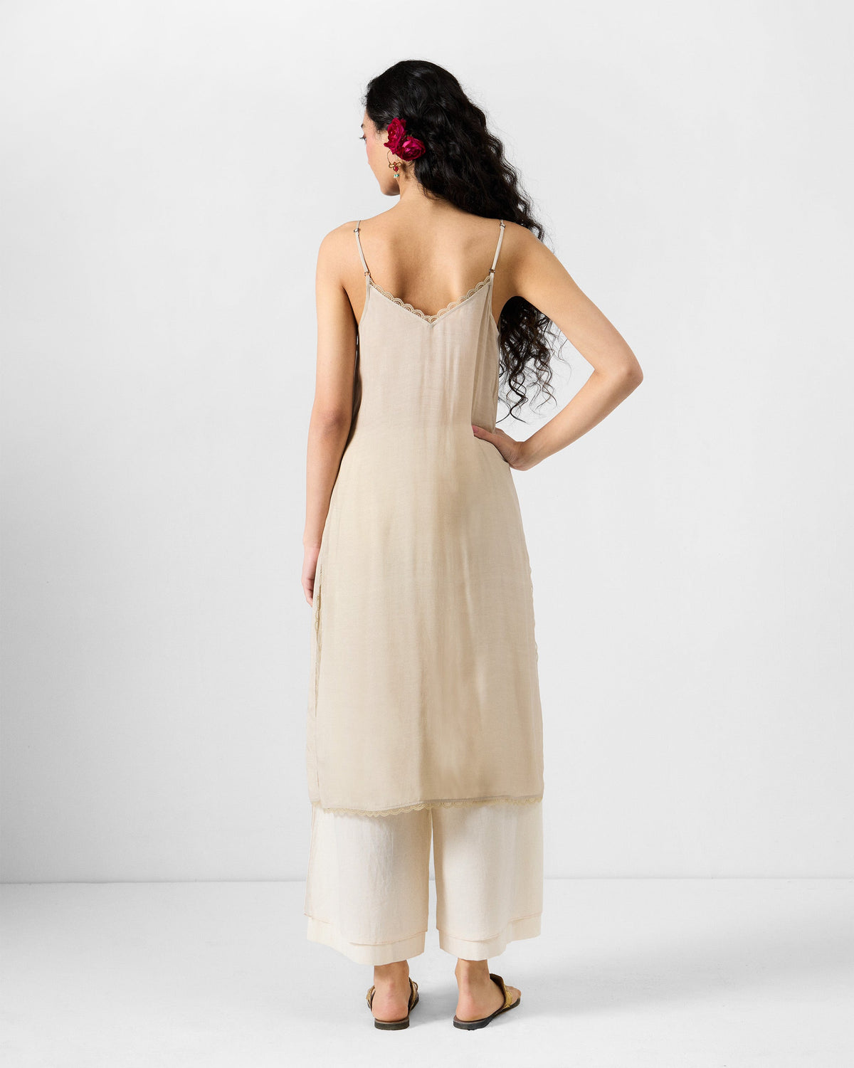 Back of an ivory Kolad kaftan slip with thin straps and lace trim.