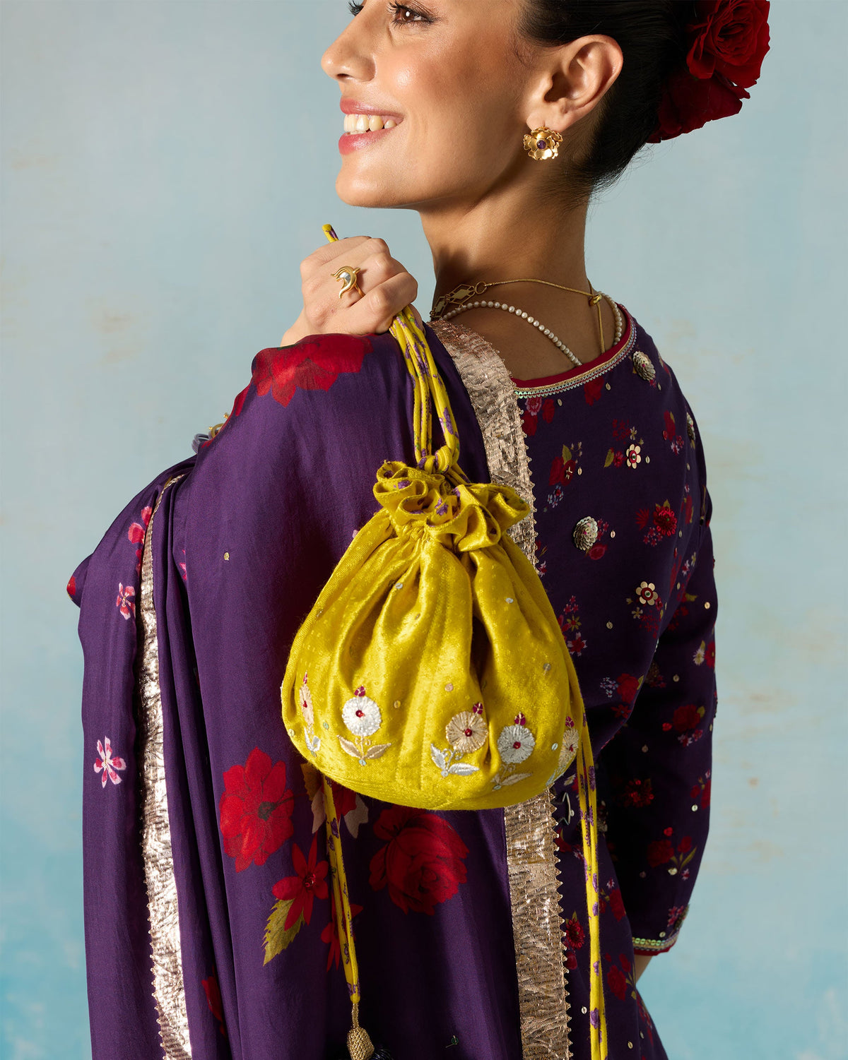 Chartreuse Firefly Potli with embroidered flowers held at the shoulder.
