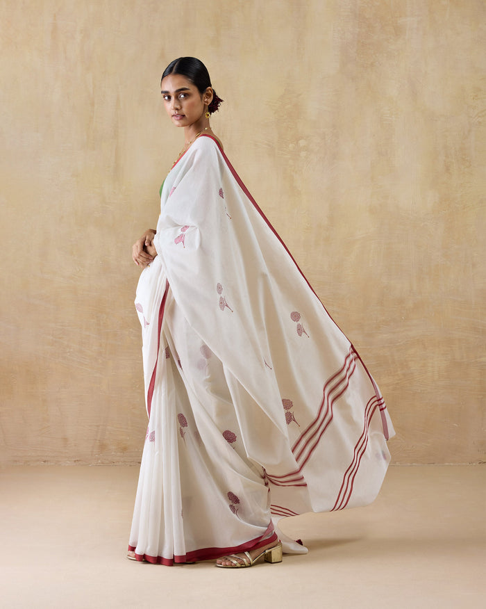 Person wearing an ivory Stardust sari with pink florals and a red border.