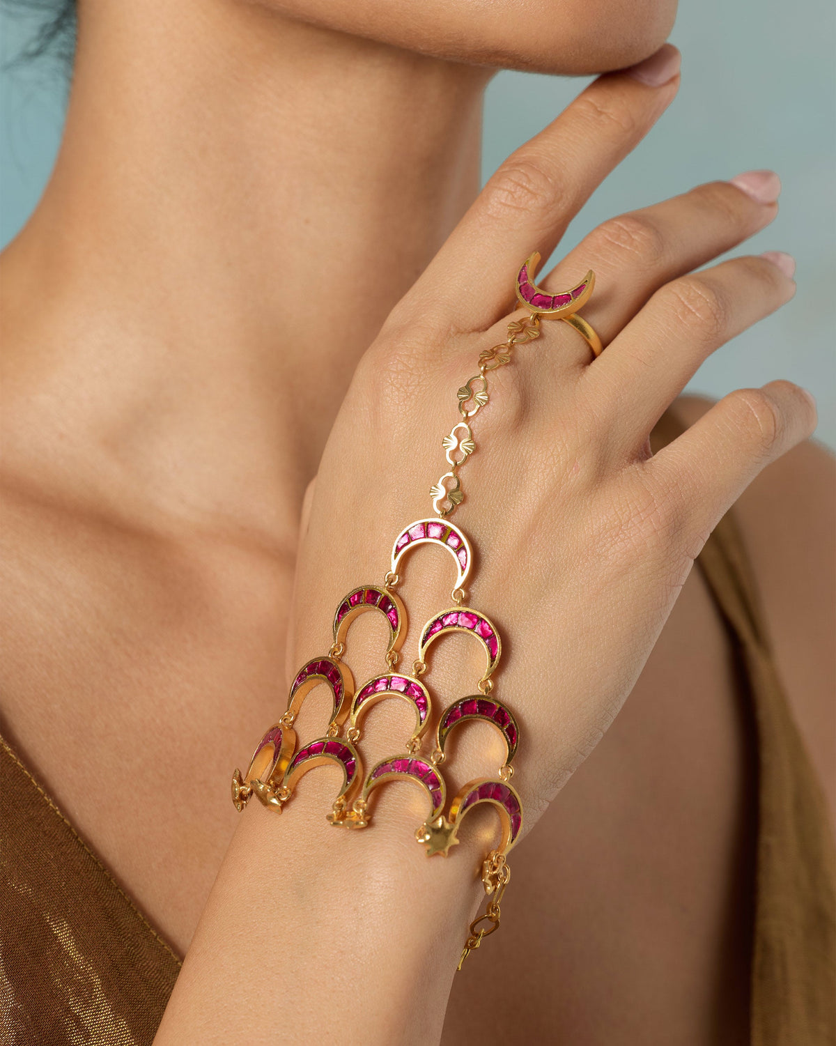 Close-up of a gold Gul Haathphool with pink crescent motifs worn on the hand.