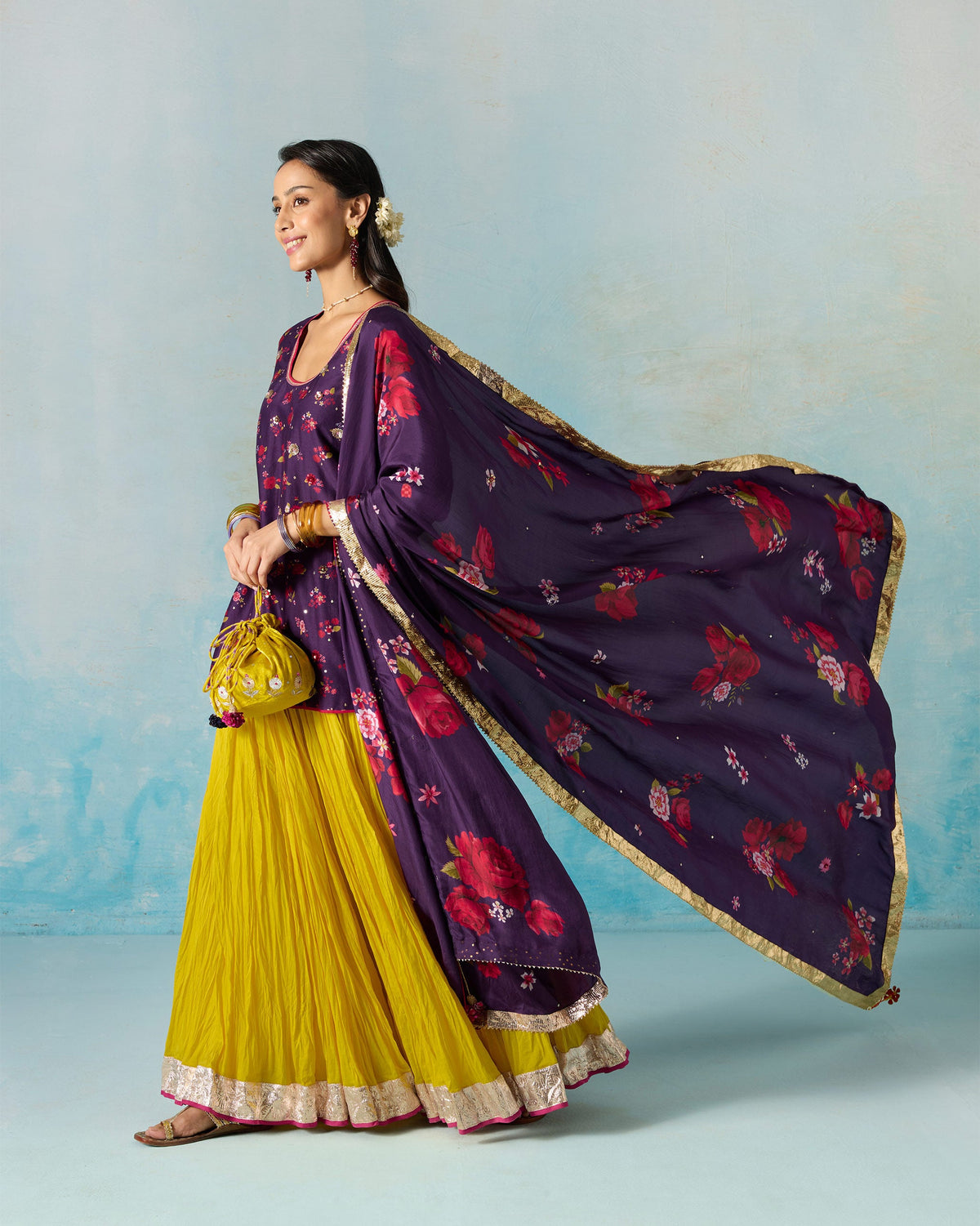 Person in a yellow Berura skirt with a gold border, styled with a purple top.